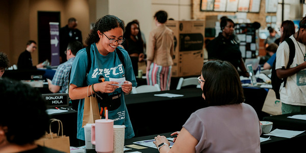 student at expo talking to staff at table